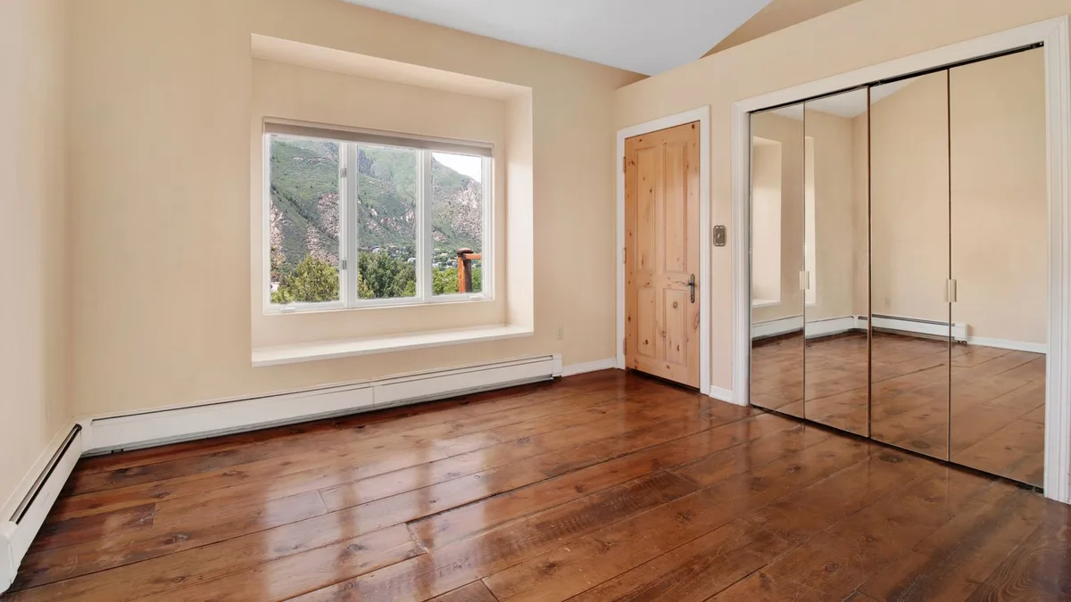 An empty bright living room with large windows and hardwood floors, real estate interior photography