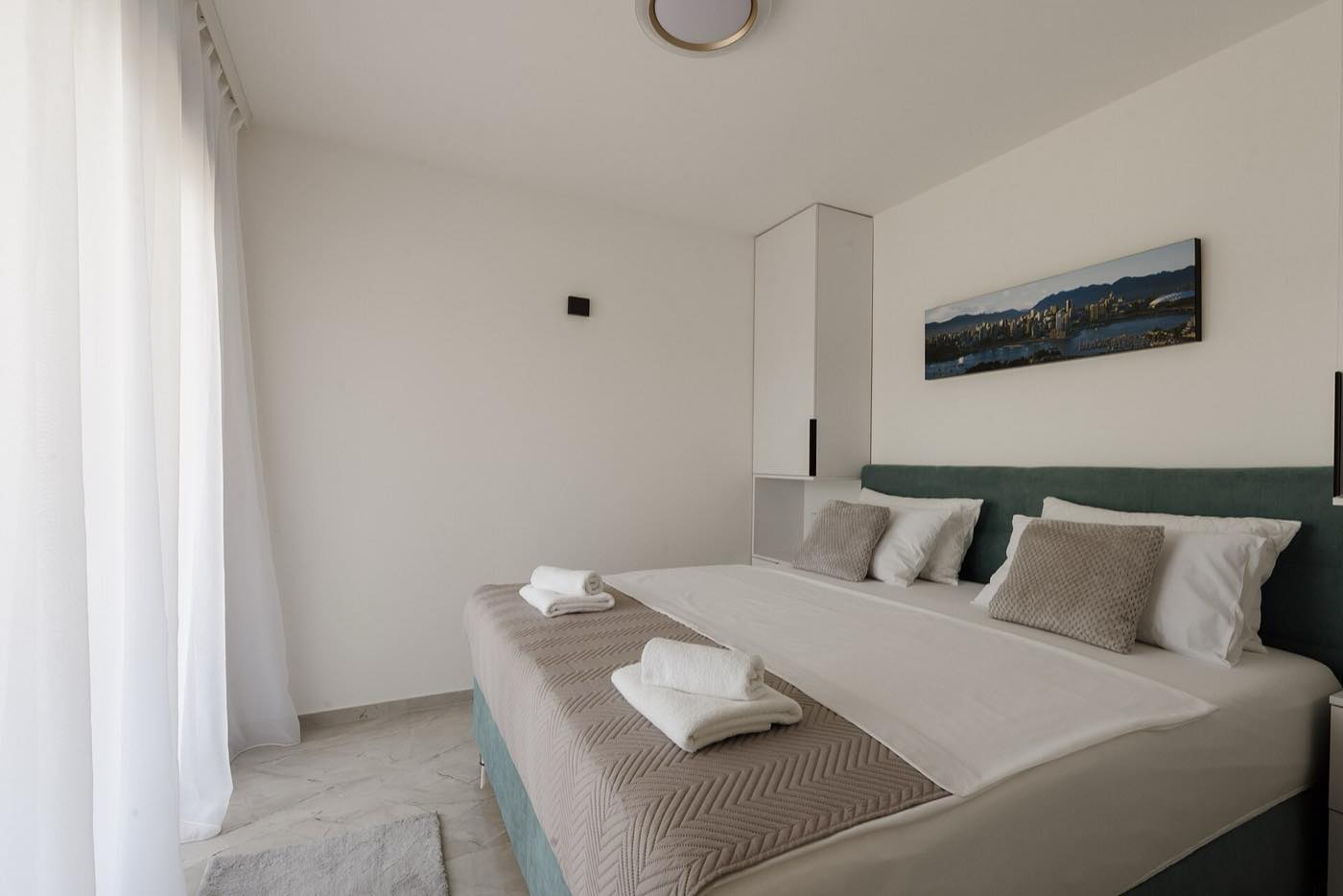 A single wide framed panorama hung above a bed in a bright bedroom