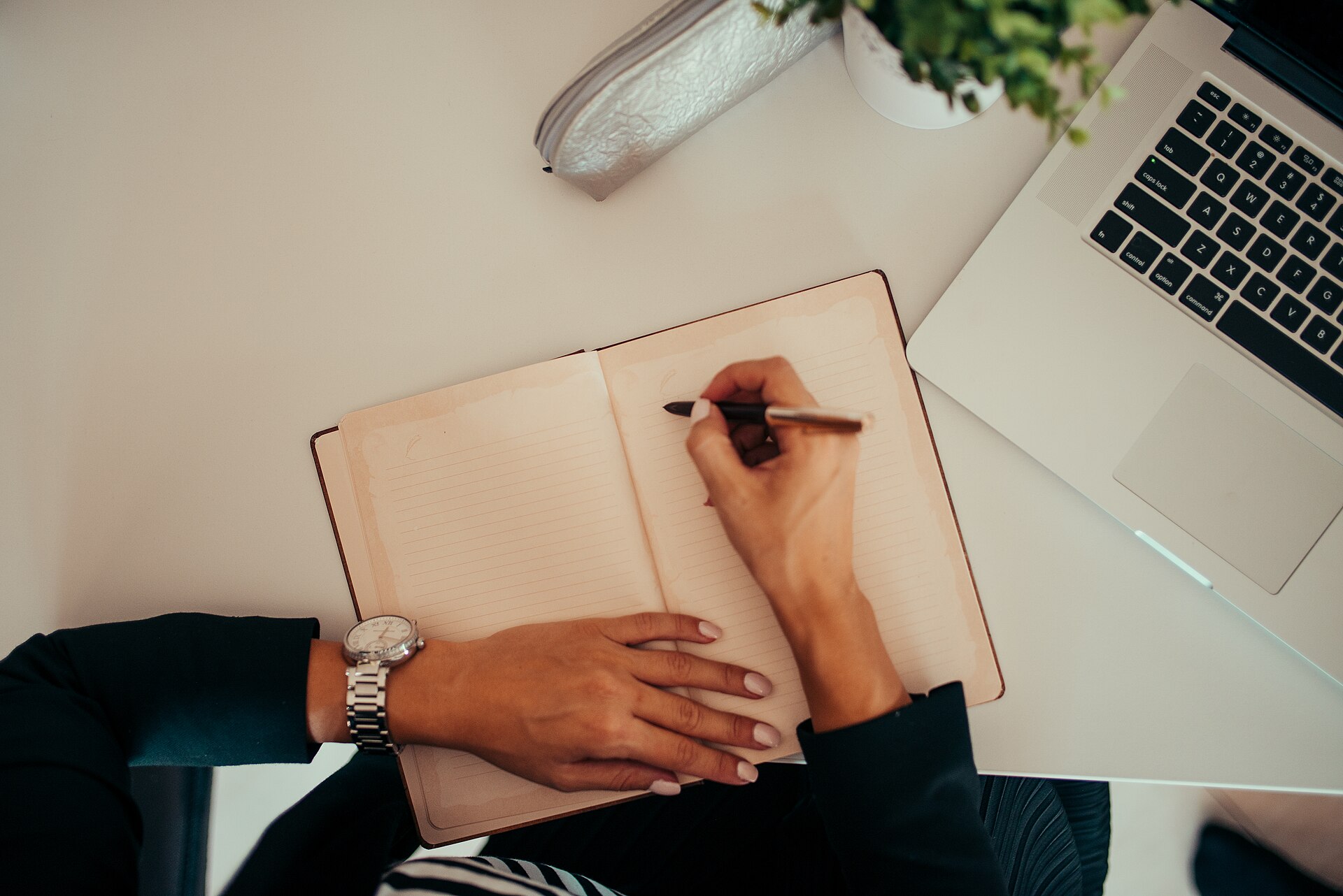 Someone iterating on ideas in a notebook beside a laptop