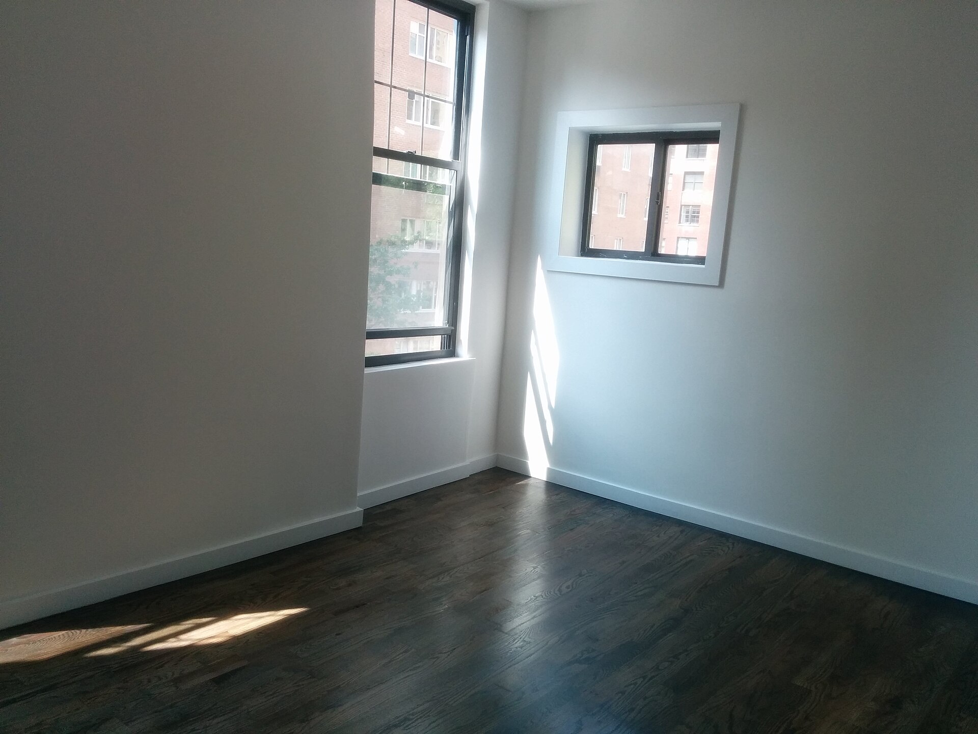 An empty rented room before any styling, with plain walls and a wooden floor