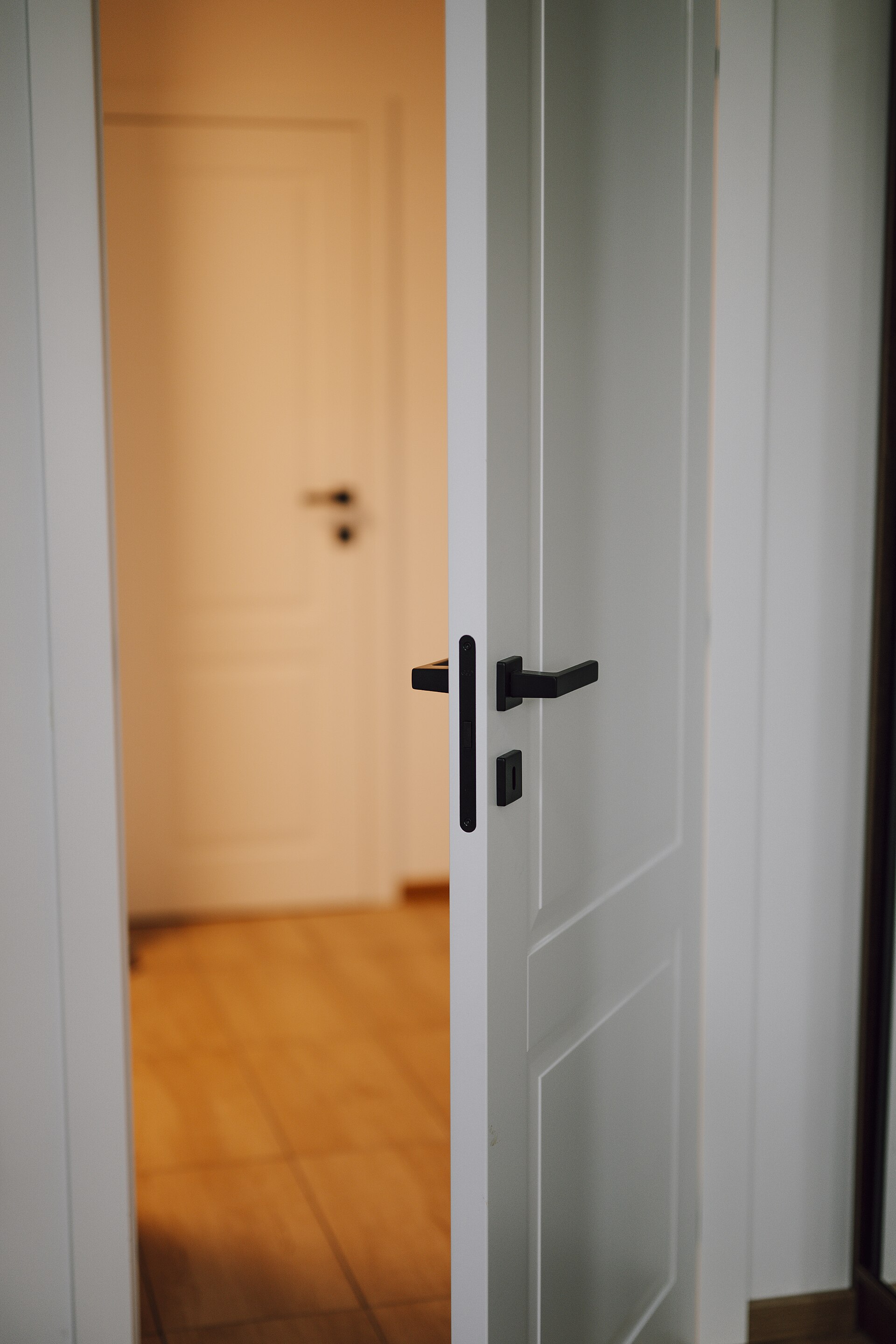 A door opening into a warmly lit room with a wooden floor