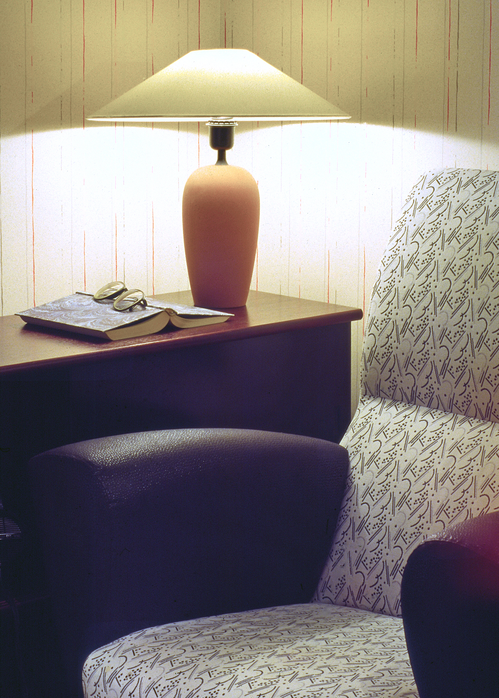 A reading corner with an armchair and a warm table lamp glowing against the wall