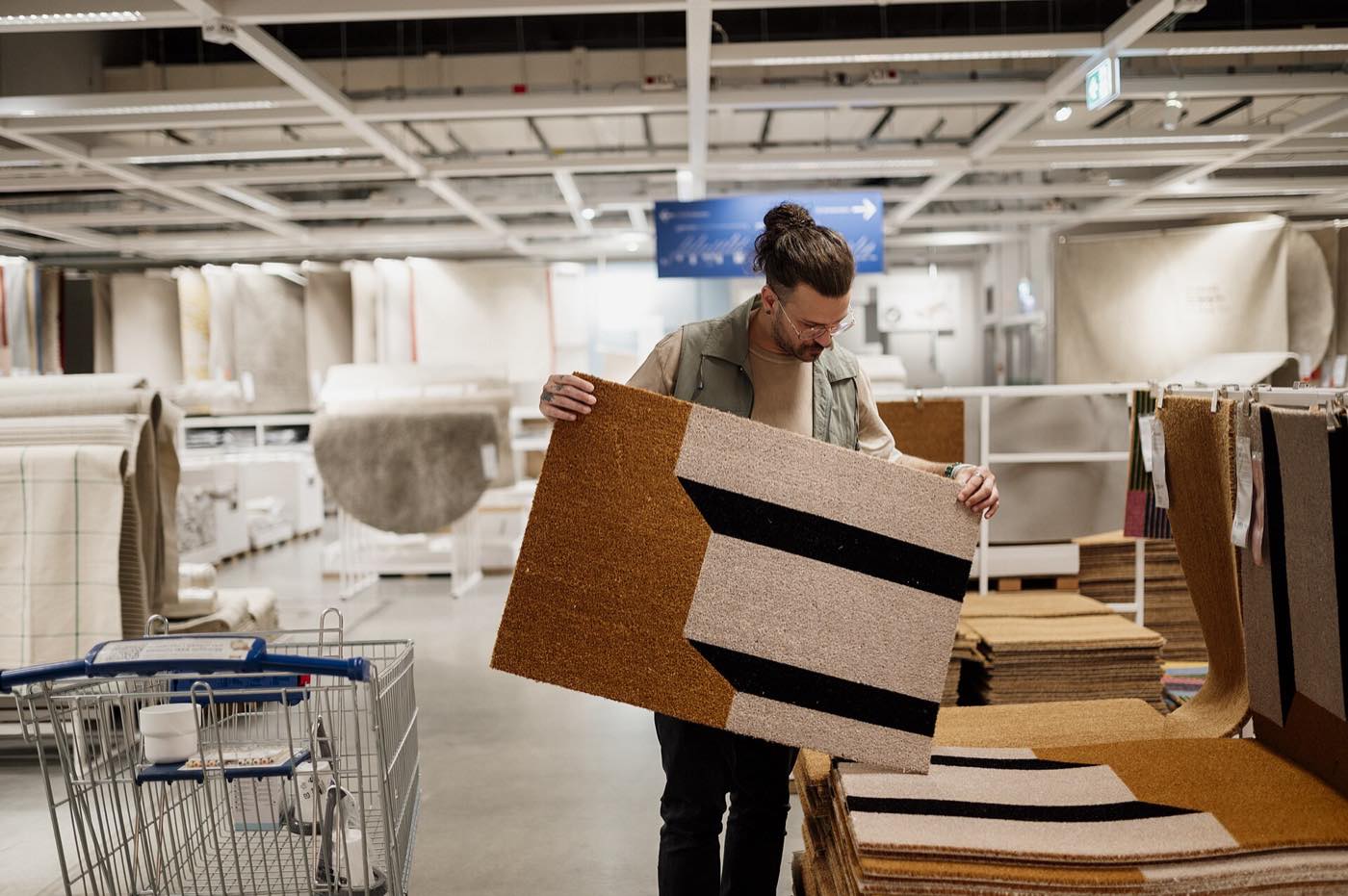 A person in a home furnishings store holding up a rug sample to judge it
