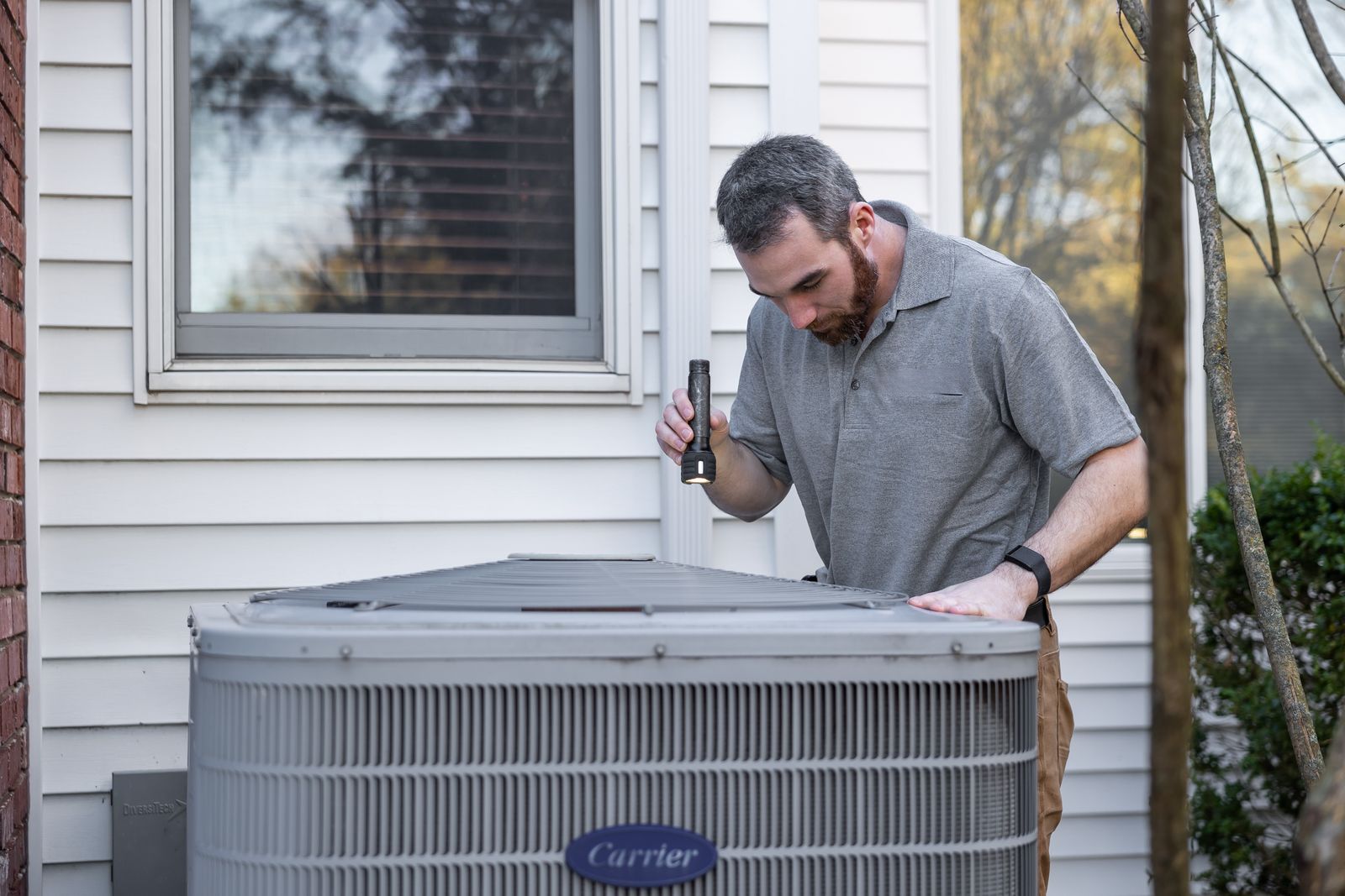 An HVAC technician servicing an outdoor air conditioning unit on a job