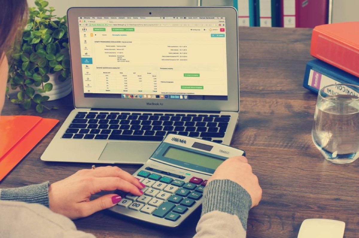 A desk with a calculator, laptop and paperwork for job admin
