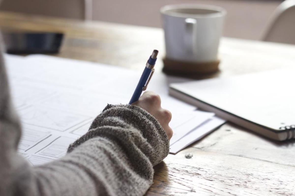 A person writing by hand in an open journal