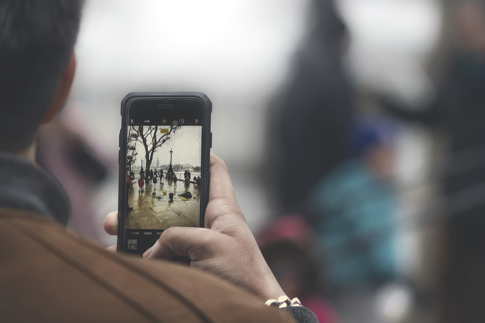 A person taking a photo of a rainy riverside street on their phone