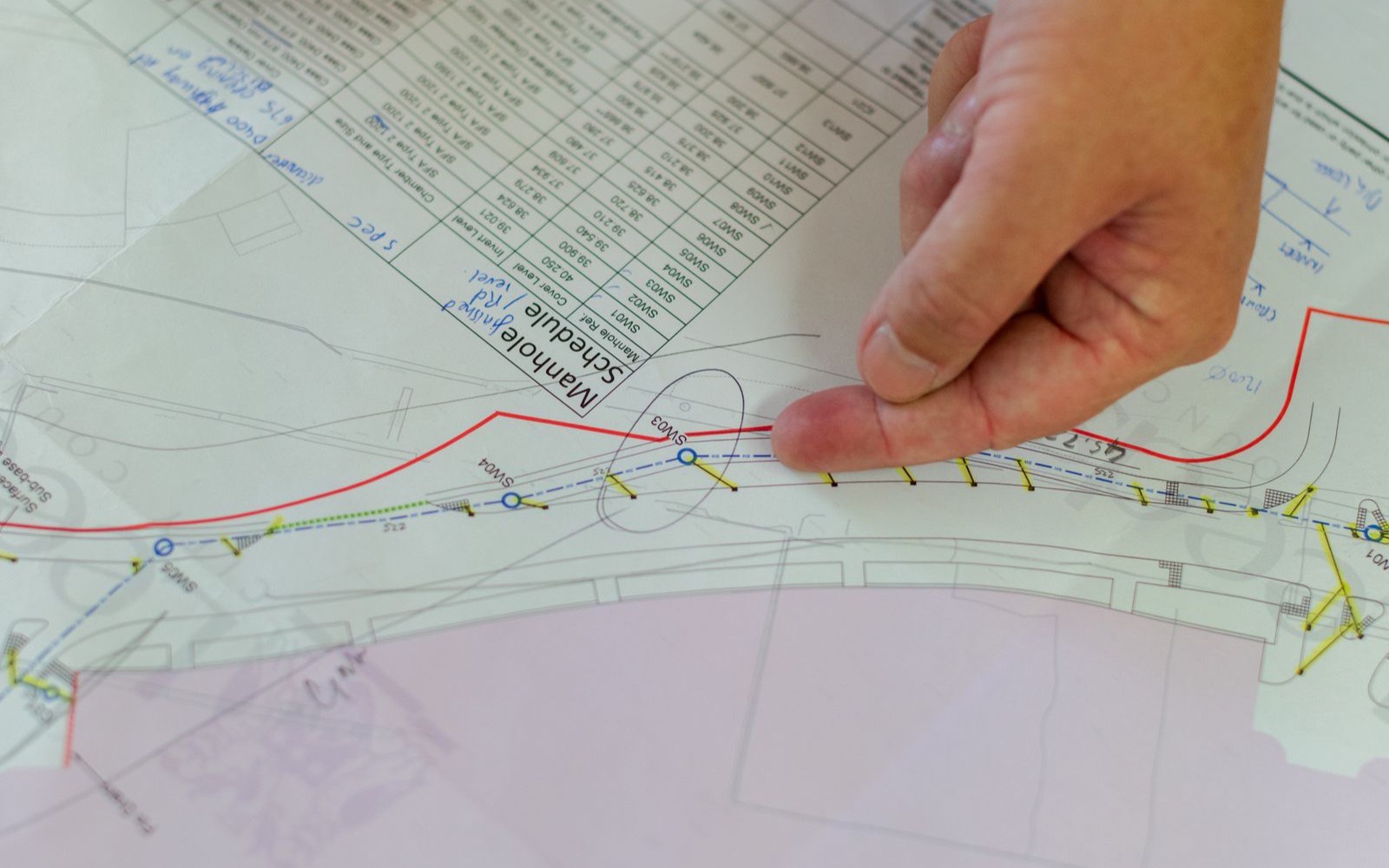 A hand checking dimensions on a detailed technical drawing
