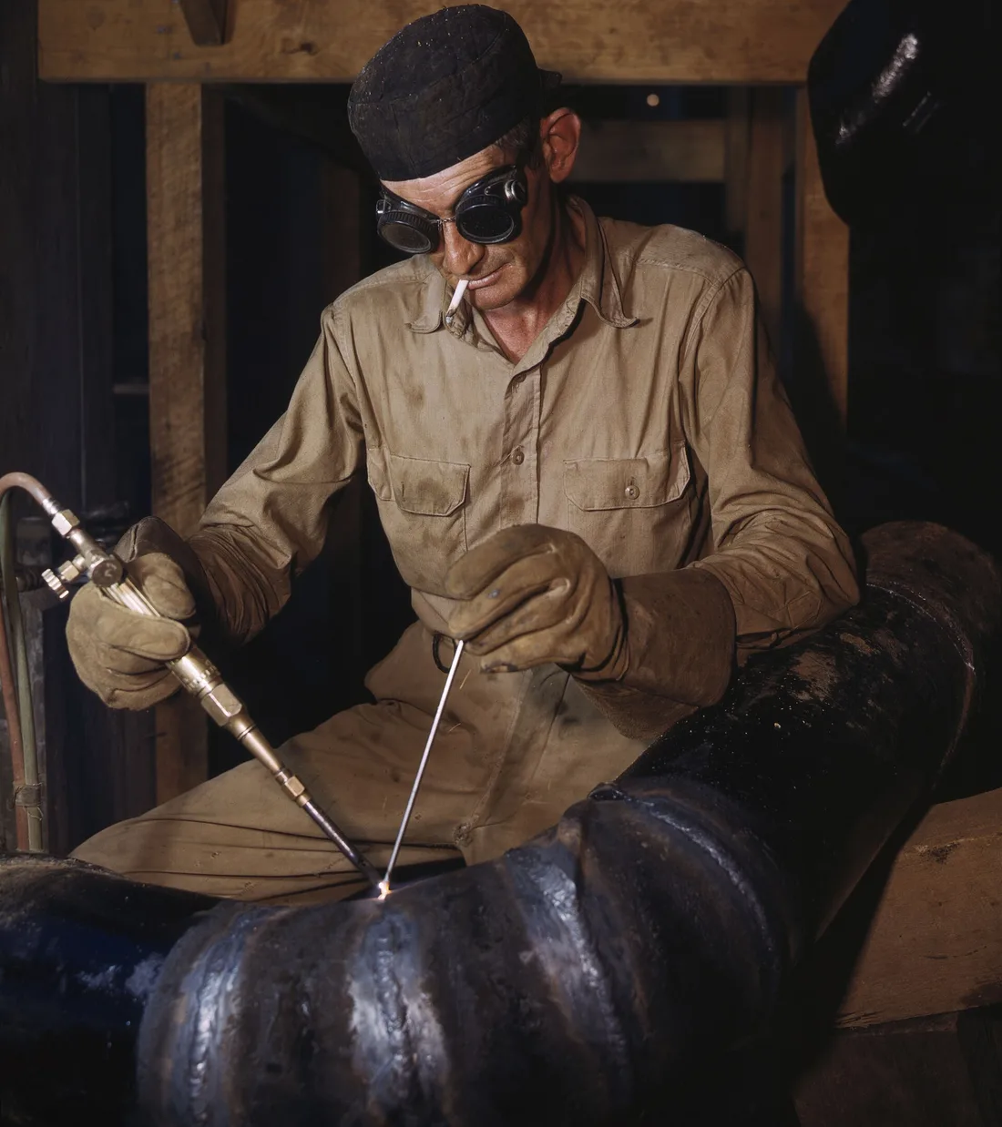 A welder in 1943 gas welding a joint in a large spiral pipe at the TVA Douglas Dam, the kind of joint a welding symbol describes